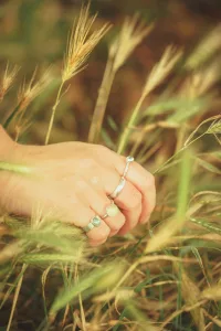 A Ladies Hand Holds Long Grass Wearin A Full Set Of Rings
