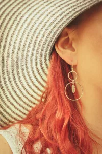 Feather Hoop Earrings On A Lady Wearing A Large Hat