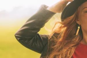 Lady holds her hat in the wind while wearing Hammered Drop Earrings