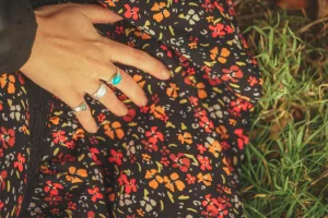 Dress blows in the wind while a hand wears a Ring Set